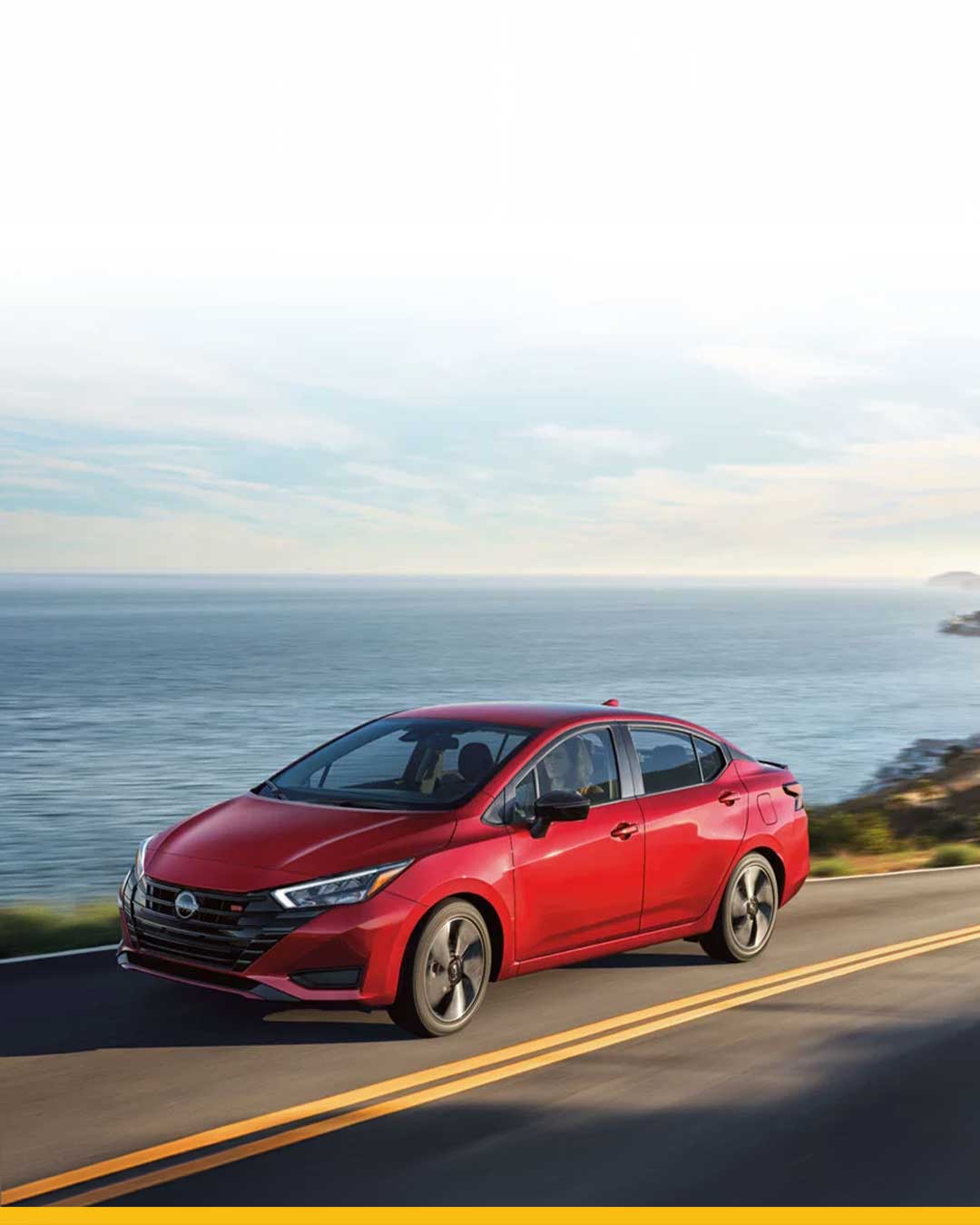 red nissan versa driving on highway by ocean